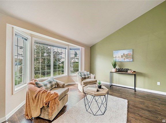 Vaulted living room with bay window is flooded with light.