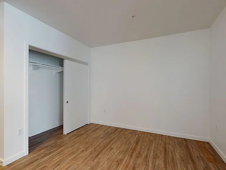 Spacious apartment bedroom with wood-style flooring.