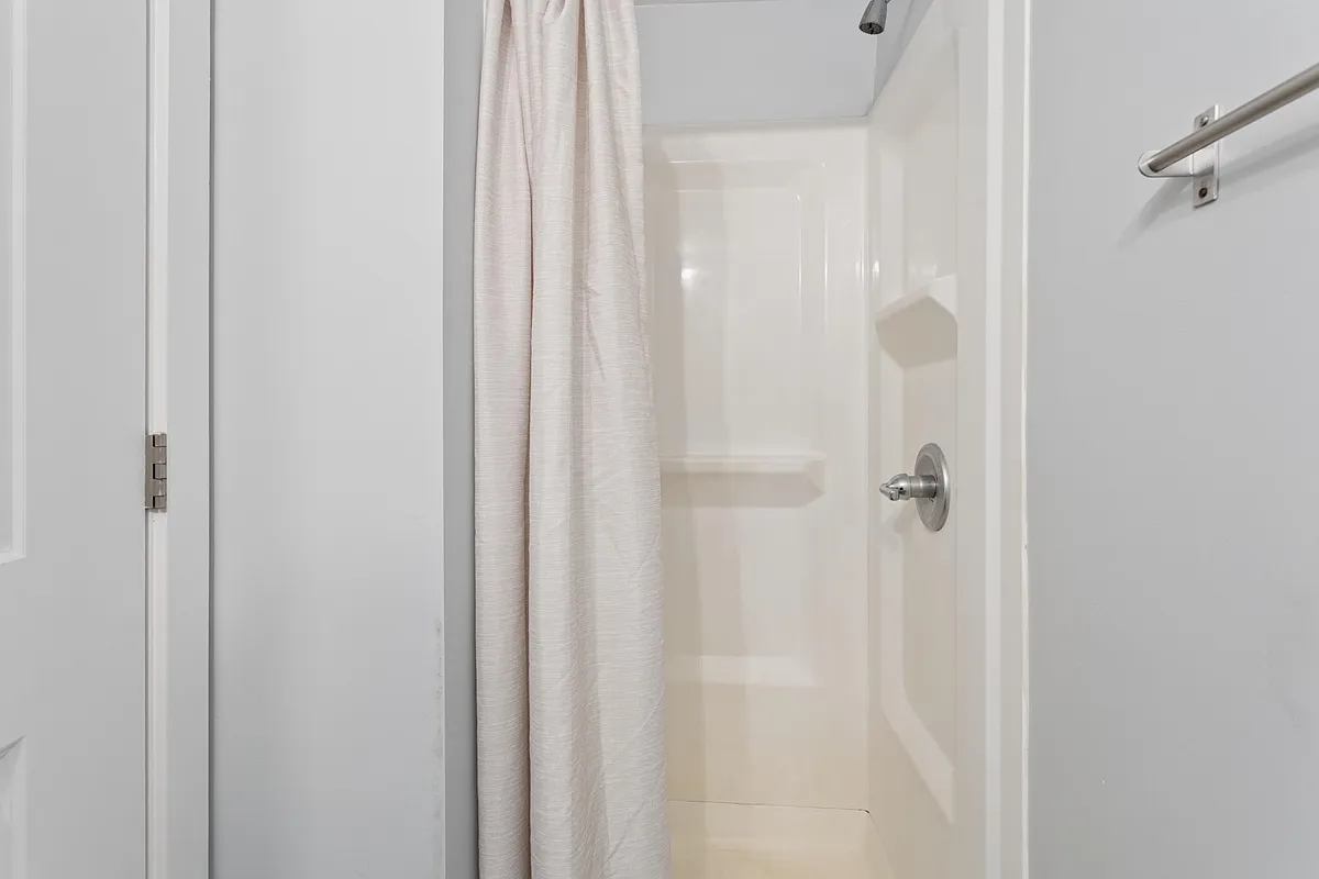 Standard tub/shower combo with integrated shelving and a shower curtain for easy, low-maintenance daily use. - W Oxford St