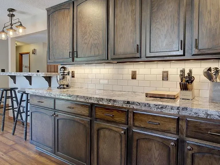 Updated granite countertop, wood flooring, and tile backsplash