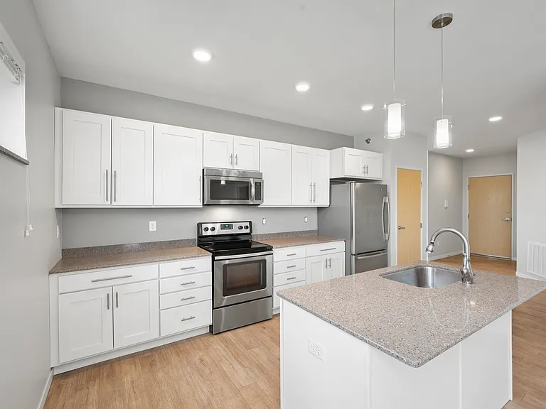 Modern kitchen with stainless steel appliances, white cabinetry, and a sleek island centerpiece, offering both style and functionality. Modern kitchen with stainless steel appliances, white cabinetry, and a sleek island centerpiece, offering both style an