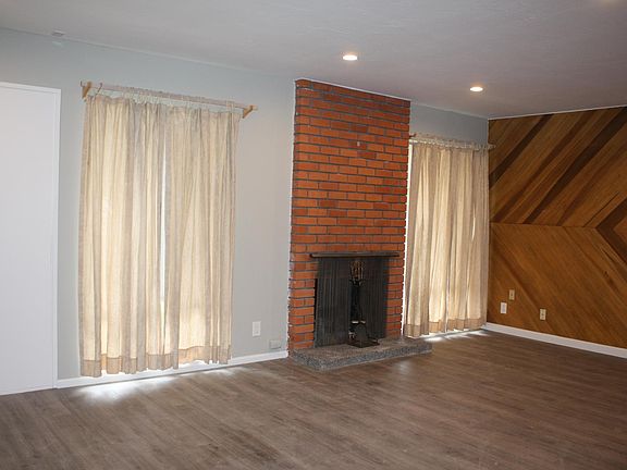 Living room with brick fireplace and custom wood paneling.