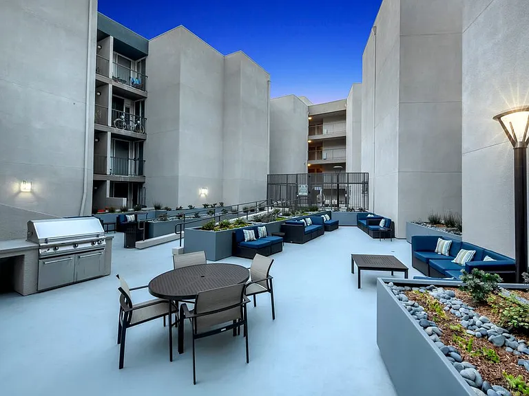 Resident courtyard with barbecue grills, fire pits, and lounge seating at dusk