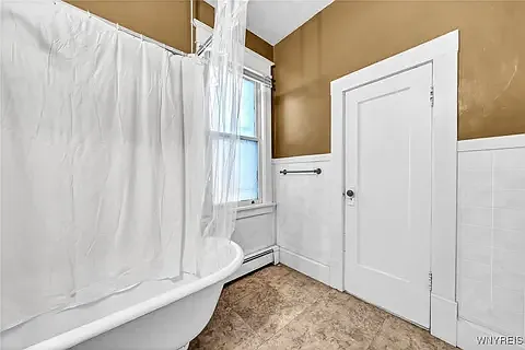 Extra large bathroom features low maintenance waterproof vinyl tile floor, door is to walk in storage/ linen closet.