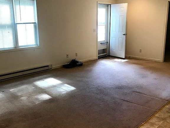 Livingroom area, opens to front door and driveway. Picture taken prior to new carpet getting installed. 11 feet by 20 feet 6 inches. Cable hook up available. Blinds on windows included. Ceiling fan. To the left, not in photo is second door that lead