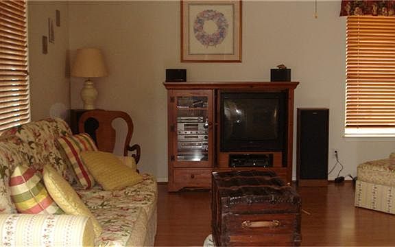 Den with wood laminate floors has fireplace