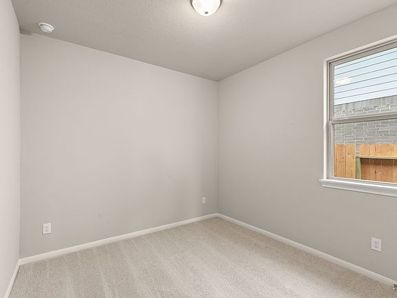 The third bedroom features plush carpet, fresh paint and a large window.