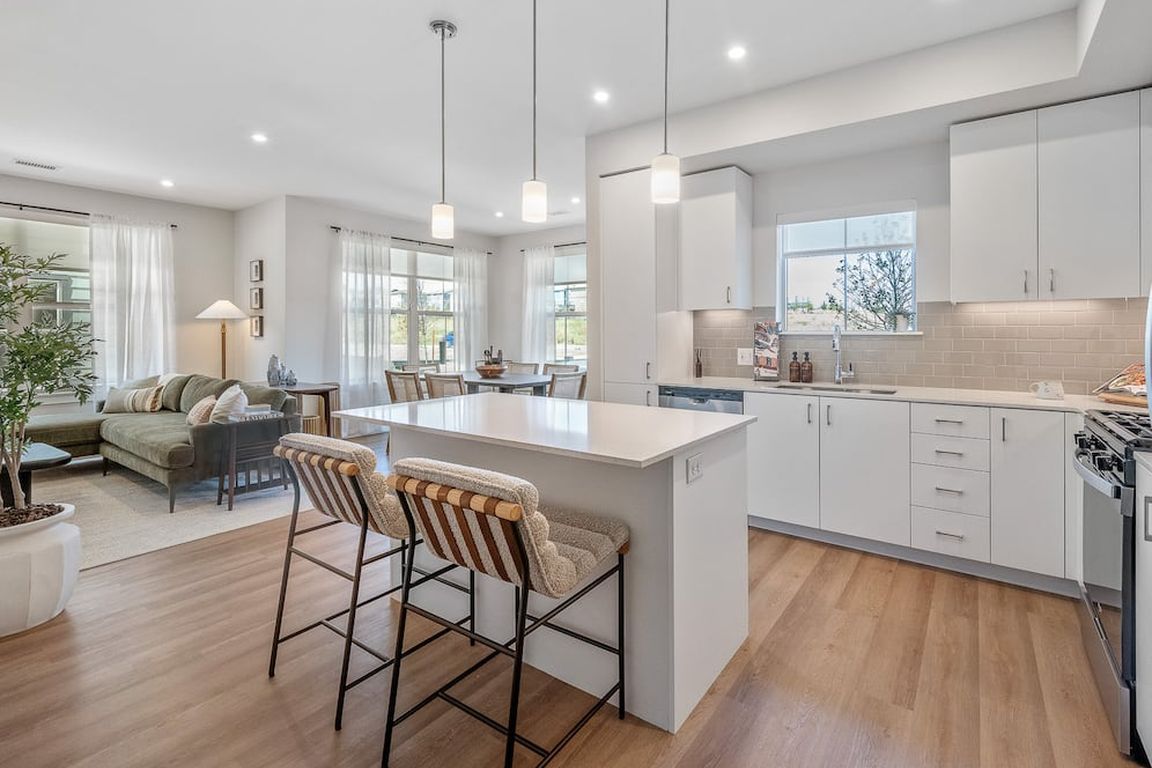 Finish Package I kitchen with stainless steel appliances, white cabinetry, grey tile backsplash, white quartz countertops, and hard surface flooring