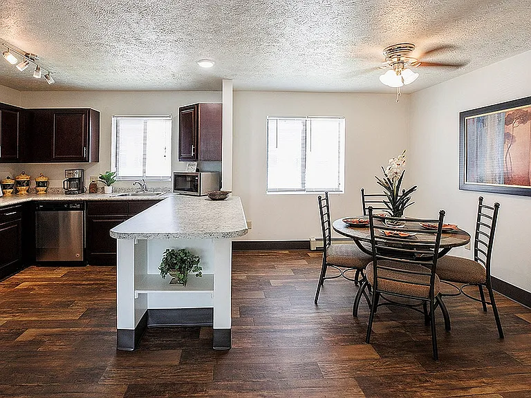 Modern kitchen with dark wood cabinets and island adjacent to an elegant dining area featuring stylish decor and warm lighting.