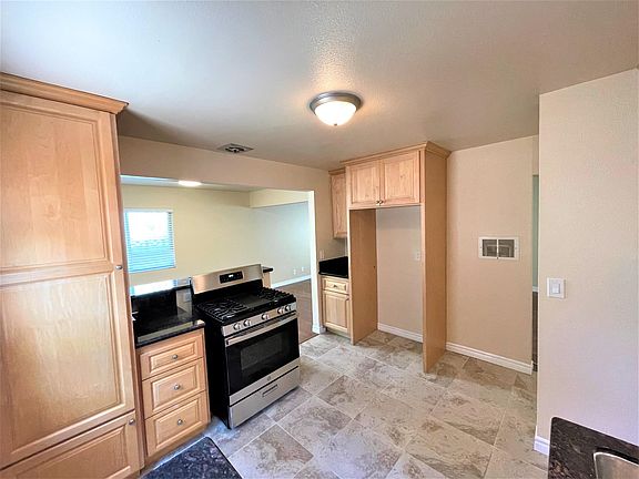 Kitchen with tile flooring, maple cabinets, granite counters and new stainless range.