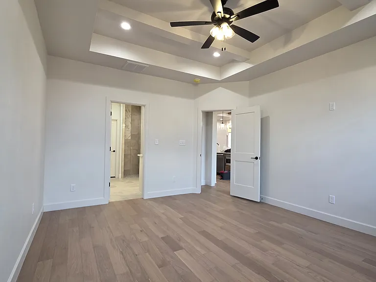 Primary/Master Bedroom featuring a tray ceiling and ceiling fan with hardwood floors