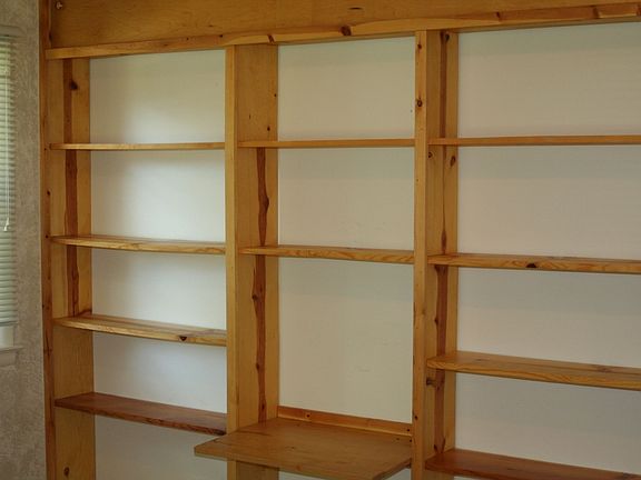 Floor to ceiling book shelves & desk span entire length of wall in leopard rm