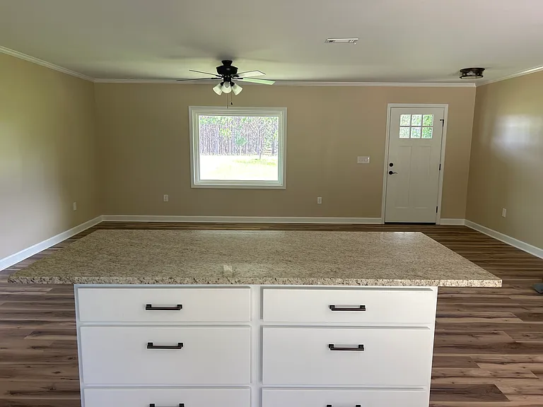 Large open floor plan. View from kitchen overlooking living room with large picture window and ceiling fan. Livingroom is spacious and large enough for a sectional couch.