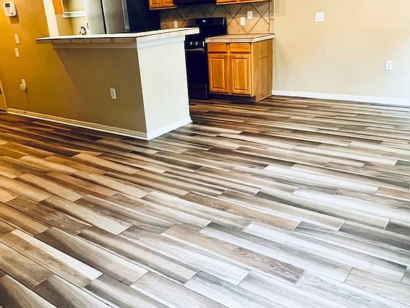 Wood-grained tile. Open format living / dining / kitchen. Pantry and room with washer & dryer are behind kitchen.