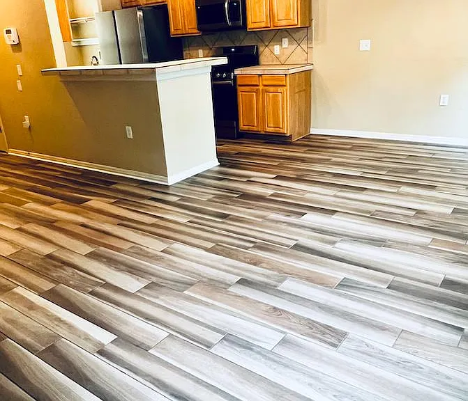 Wood-grained tile. Open format living / dining / kitchen. Pantry and room with washer & dryer are behind kitchen.
