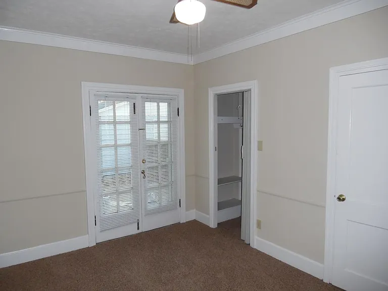 Bedroom #2 faces the back of the house. French doors to back yard. Walk in closet with built in shelving. Closed door leads to half bath.