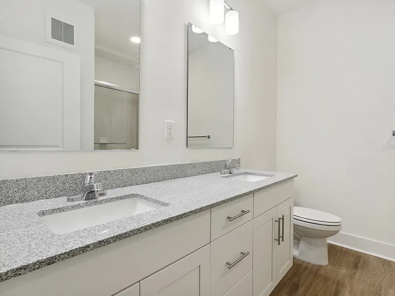 Elegant bathroom with dual sinks, granite countertops, and modern fixtures, offering a sleek and refreshing space.