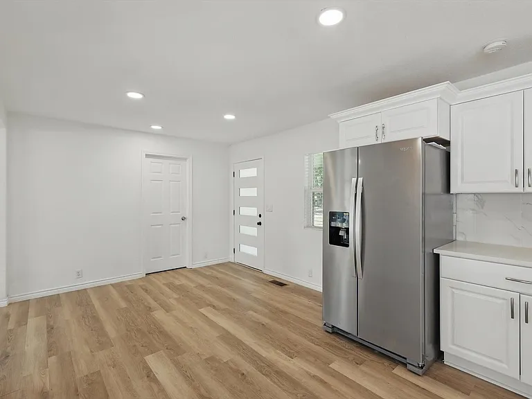 Kitchen with stainless steel fridge with ice dispenser, light wood-style floors, white cabinets, and recessed lighting