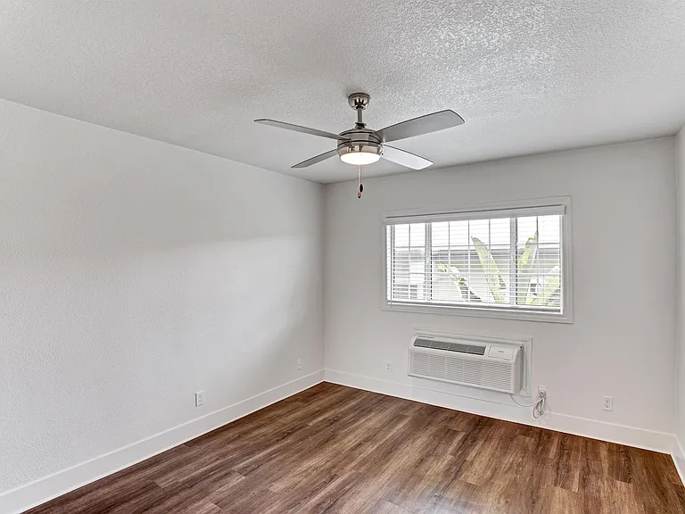 A room with a ceiling fan and a window with blinds.