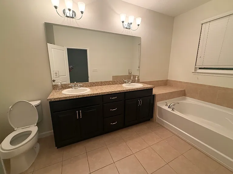 Primary bathroom with double vanity, granite countertop and soaking tub.