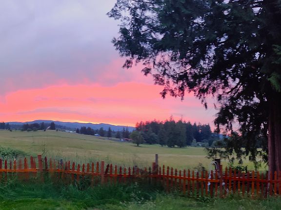 Cattle pasture with big barn along I-5 with sunset behind Black Hills beyond.