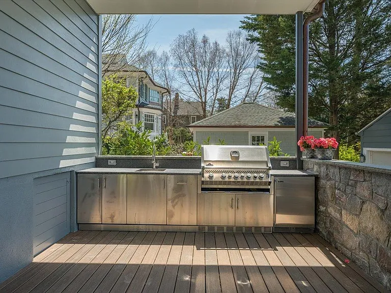 Custom built-in stainless steel outdoor kitchen with fridge, BBQ, sink, trash and recycling.