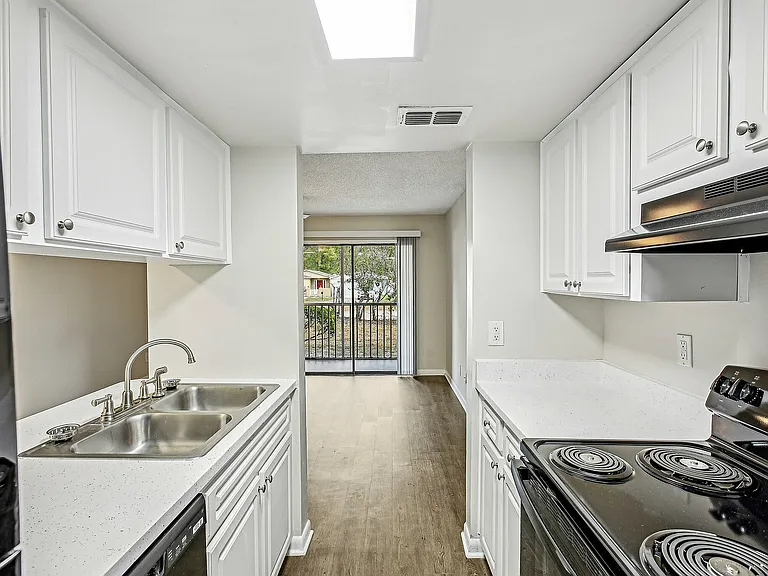 Galley-style kitchen with bright finishes and balcony view.