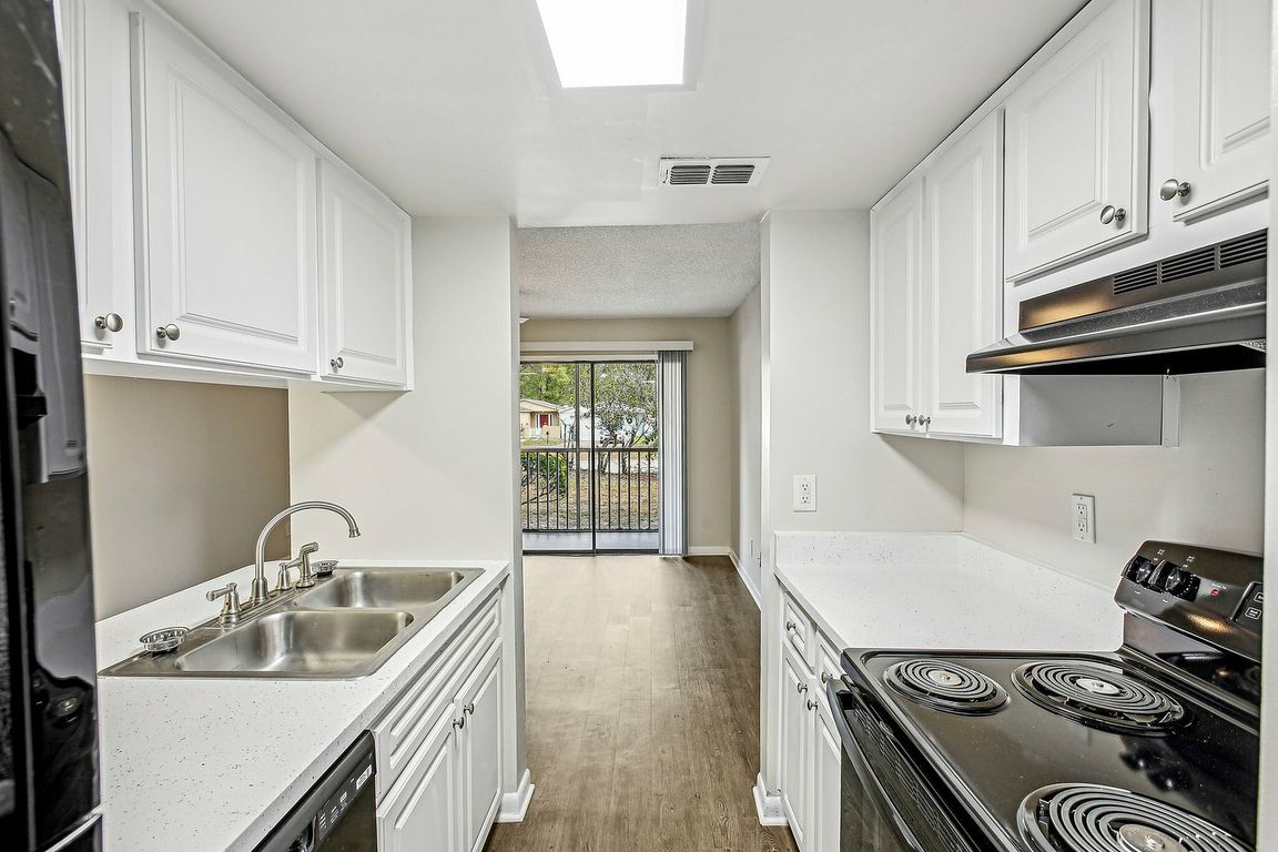 Galley-style kitchen with bright finishes and balcony view.