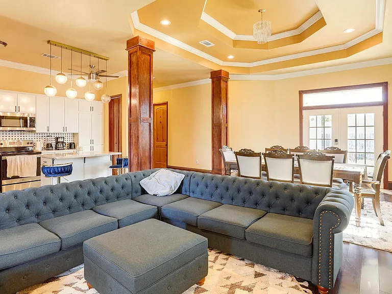 Open-concept main level with a large sectional seating area, adjacent dining space, and a kitchen with ample cabinetry.