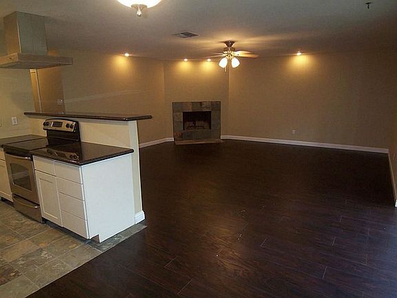 Open living room has extra added warm lighting and hard wood floors.