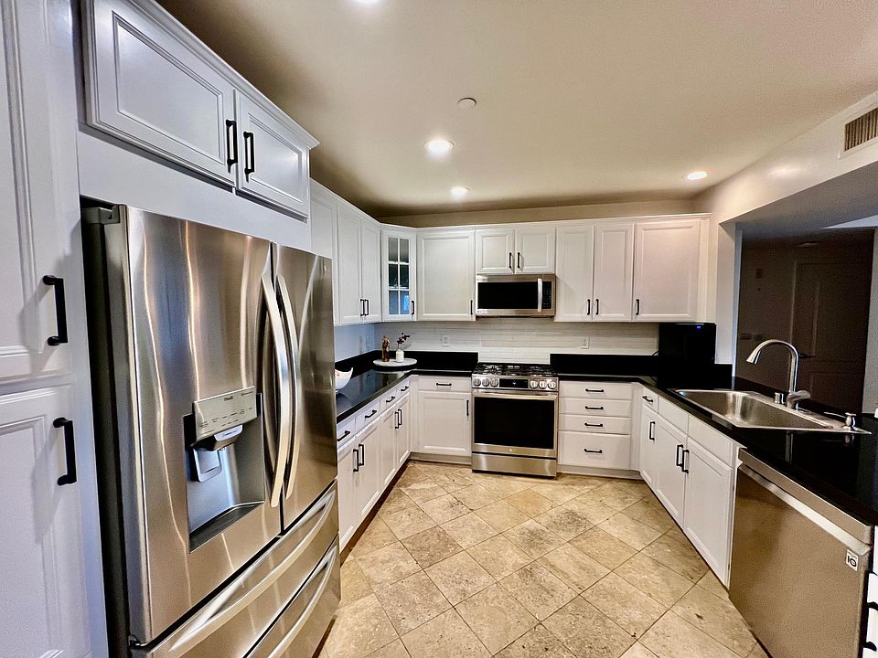 Open-concept kitchen with updated LG appliances, new backsplash, white resurfaced cabinets and new black hardware