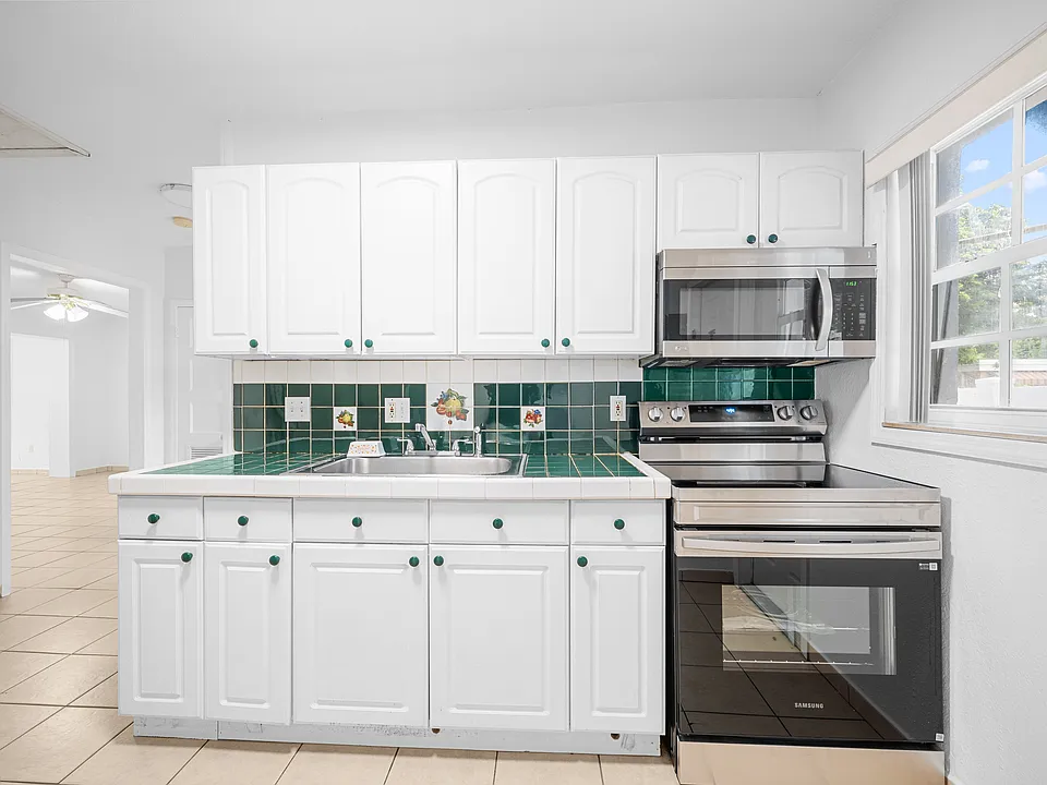 Kitchen - Updated kitchen equipped with white cabinetry, durable countertops, built-in microwave, and stainless steel range.