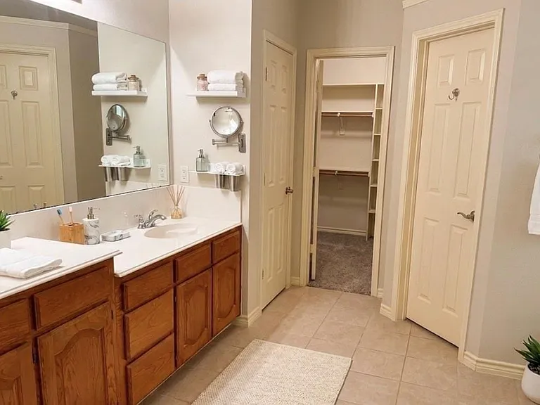 Bathroom vanity with dual undermount sinks, light-toned countertop, and wood-finish cabinetry