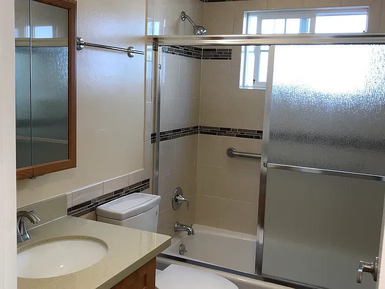 The bathroom has Corian countertop, rich maple cabinets and vanity, porcelain floor tile and a bathtub with shower.