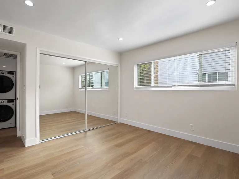 Bedroom with Large Mirrored Closet and Window Providing Natural Light