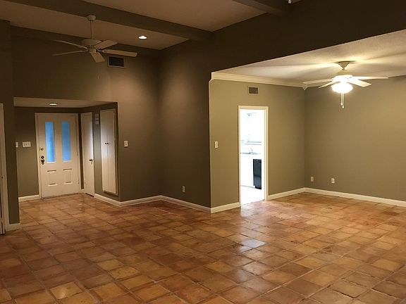 Another view of the living room and front door, as well as dining room and kitchen entrance.