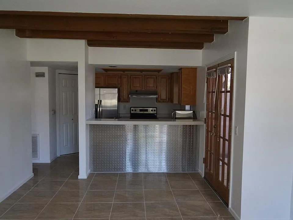 Kitchen with bar and sink facing living room. French doors exit to the back patio.