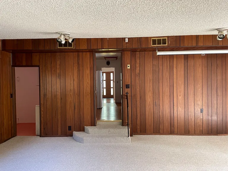 large den / multi-purpose room. Stairs back up to kitchen, doorway on left to laundry room