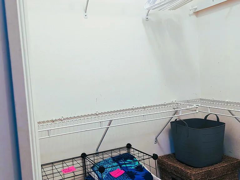 Master closet has 3 walls and shelves for clothes. Beach towels, bath towels and sheet are stored below with hamper in corner.