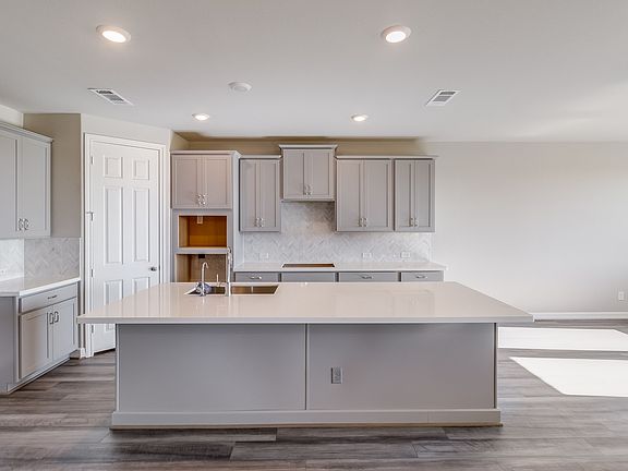 Kitchen featuring light grey cabinetry, quartz countertops and a modern tile backsplash