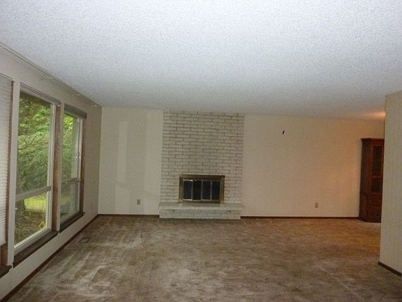 Large living room with wood burning brick fireplace. In the downstairs family room there is also a s