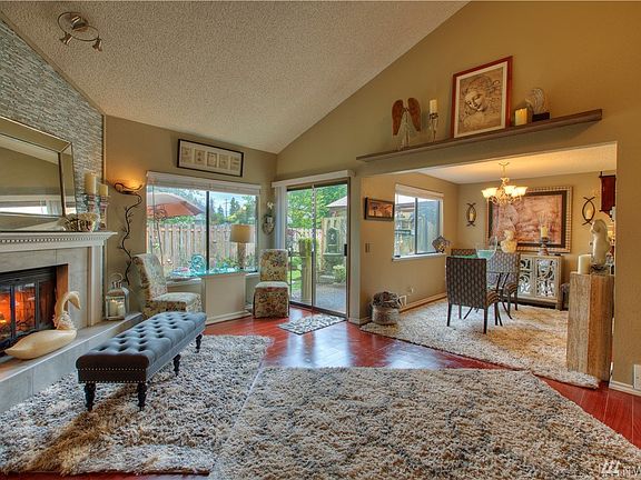 Spacious living room with glowing wood fireplace, looking into the dining room.
