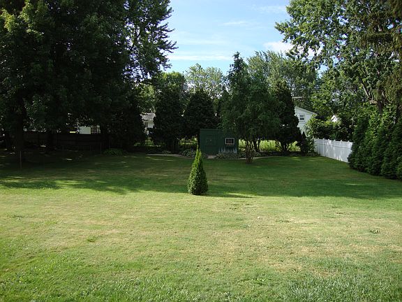 Large back lawn with privacy fence and adorable garden shed.