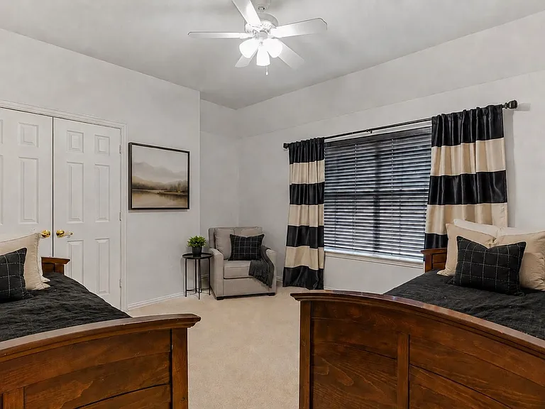 Carpeted room featuring a ceiling fan, window with blinds, and white bi-fold closet doors