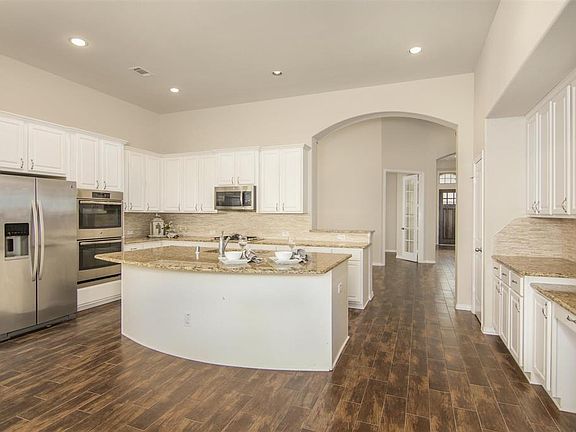 Open kitchen with and abundance of cabinets located behind island and side wall buffet counter storage.