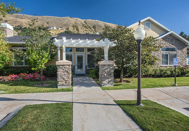 Liberty Hill Apartments, Draper, Utah, entrance with a white pergola and a stone pillar in front of it.