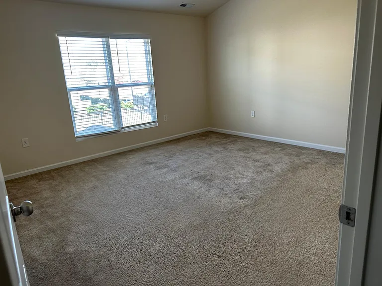 A view from the hallway into the main bedroom, which faces the back of the house. Immediately into the room on the right is the door to the main bathroom and walk in closet. The ceiling in this room is vaulted and there is a remote operated fan.