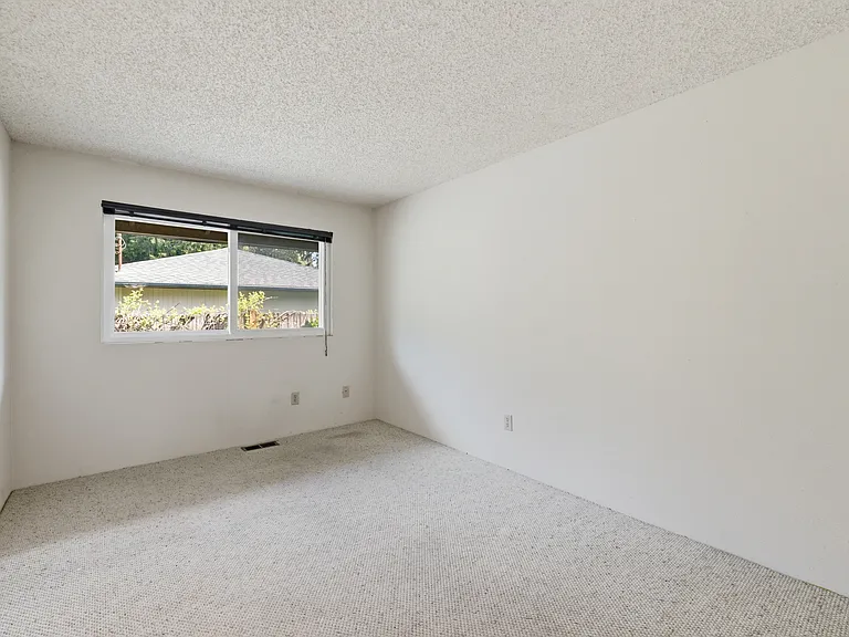 Additional bedroom with soft carpet and a window overlooking the yard