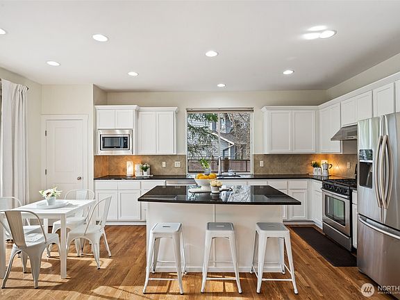 Newly remodeled kitchen boasts stainless steel appliances, crisp white cabinetry, sparkling countertops, full-height backsplash, and a 5-burner gas stove.>