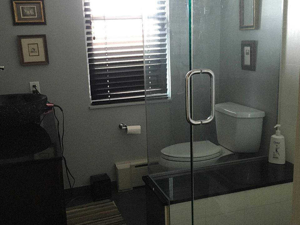 Renovated bathroom with glass enclosed shower and granite countertop